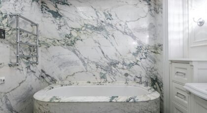 Luxurious modern bathroom with marble tub and wall, featuring elegant design elements.