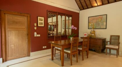 A serene Balinese dining room with vintage decor and wooden furniture, exuding warmth and elegance.