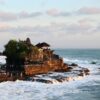 Scenic aerial view of the iconic Tanah Lot Temple on the coast of Bali, surrounded by waves.