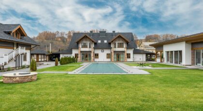 Exterior of contemporary residential cottage house with green lawn in yard under cloudy sky