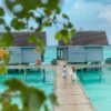 Romantic couple walking hand in hand on a wooden boardwalk with overwater villas in the Maldives.
