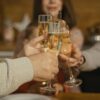 A close-up of hands raising champagne glasses in a celebratory toast indoors.
