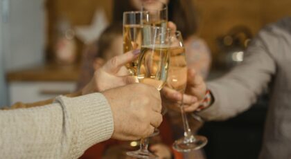 A close-up of hands raising champagne glasses in a celebratory toast indoors.