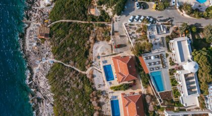 A stunning aerial shot of coastal villas, lush greenery, and sparkling blue sea.
