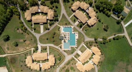 Aerial image showcasing resort villas and swimming pool in lush surroundings, Corfu, Greece.