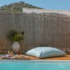 A serene poolside setup with a cushion and plants against a mountain backdrop.