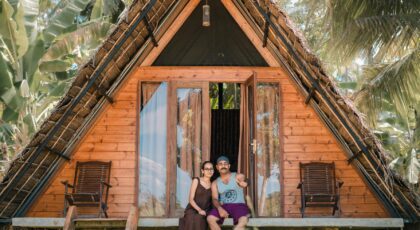 A couple enjoying the tropical view from their rustic wooden bungalow in Sri Lanka.