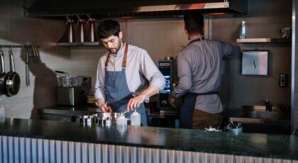 Two chefs working in an open kitchen, preparing dishes in a modern restaurant.