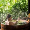 A woman enjoys a serene spa bath surrounded by lush greenery in Ubud, Bali.