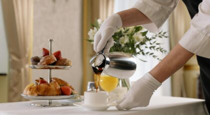 Luxurious breakfast scene with fresh pastries, coffee being poured, and elegant table setting.