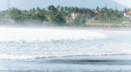 Scenic coastal view with waves and tropical vegetation in Pulukan, Bali, Indonesia.