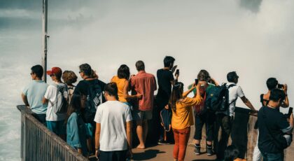 Group of tourists capturing the majestic Rhine Falls from a viewing platform in Switzerland.