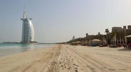 A stunning view of Burj Al Arab against the clear sky on a serene beach in Dubai, UAE.