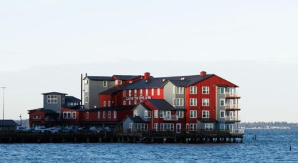 Red and grey waterfront hotel set against a serene ocean view during daylight.