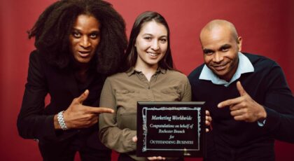 Three diverse professionals proudly pose with an award for outstanding business achievement.