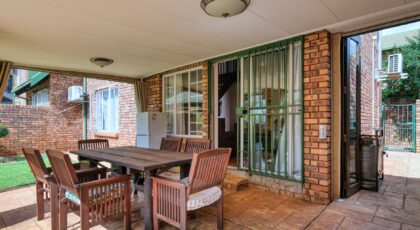 Cozy outdoor patio space with wooden furniture and brick walls in a modern home.