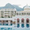 Elegant resort facade with pool, surrounded by mountains, perfect for a luxurious vacation getaway.