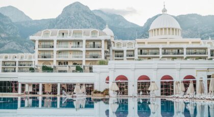 Elegant resort facade with pool, surrounded by mountains, perfect for a luxurious vacation getaway.