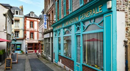 Rustic street in Normandy, France showcasing vibrant architecture and quaint storefronts.