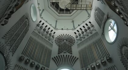 A collection of medieval weapons on display in a historic armory room with ornate design.
