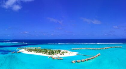 Stunning aerial view of a tropical island resort with overwater villas in the Maldives.