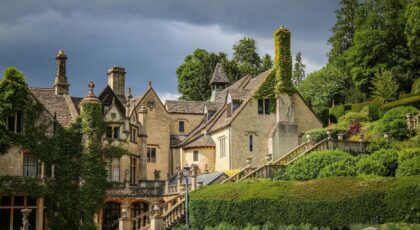 Scenic view of a historic manor house surrounded by lush green gardens in Castle Combe, England.