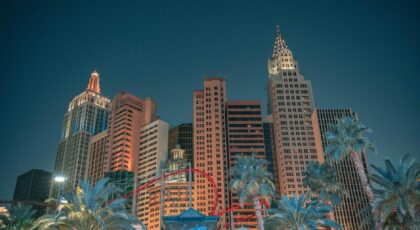 Night view of the Las Vegas skyline featuring iconic skyscrapers and an illuminated roller coaster.