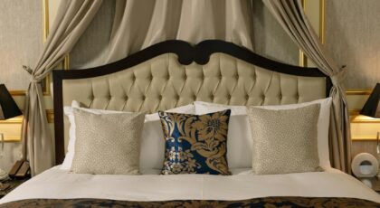Elegant hotel room with plush headboard, decorative pillows, and luxurious curtains.